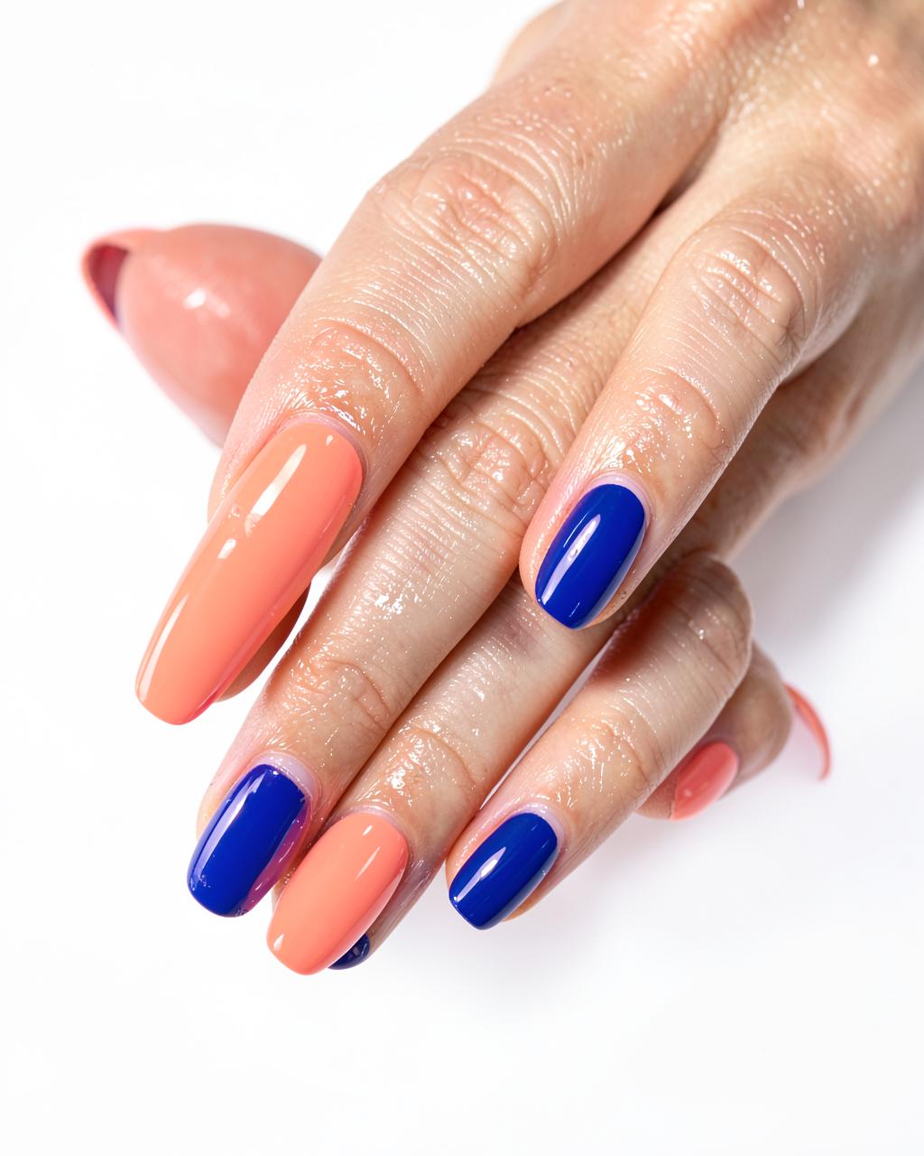 Glossy coral and cobalt blue gel manicure catching studio light